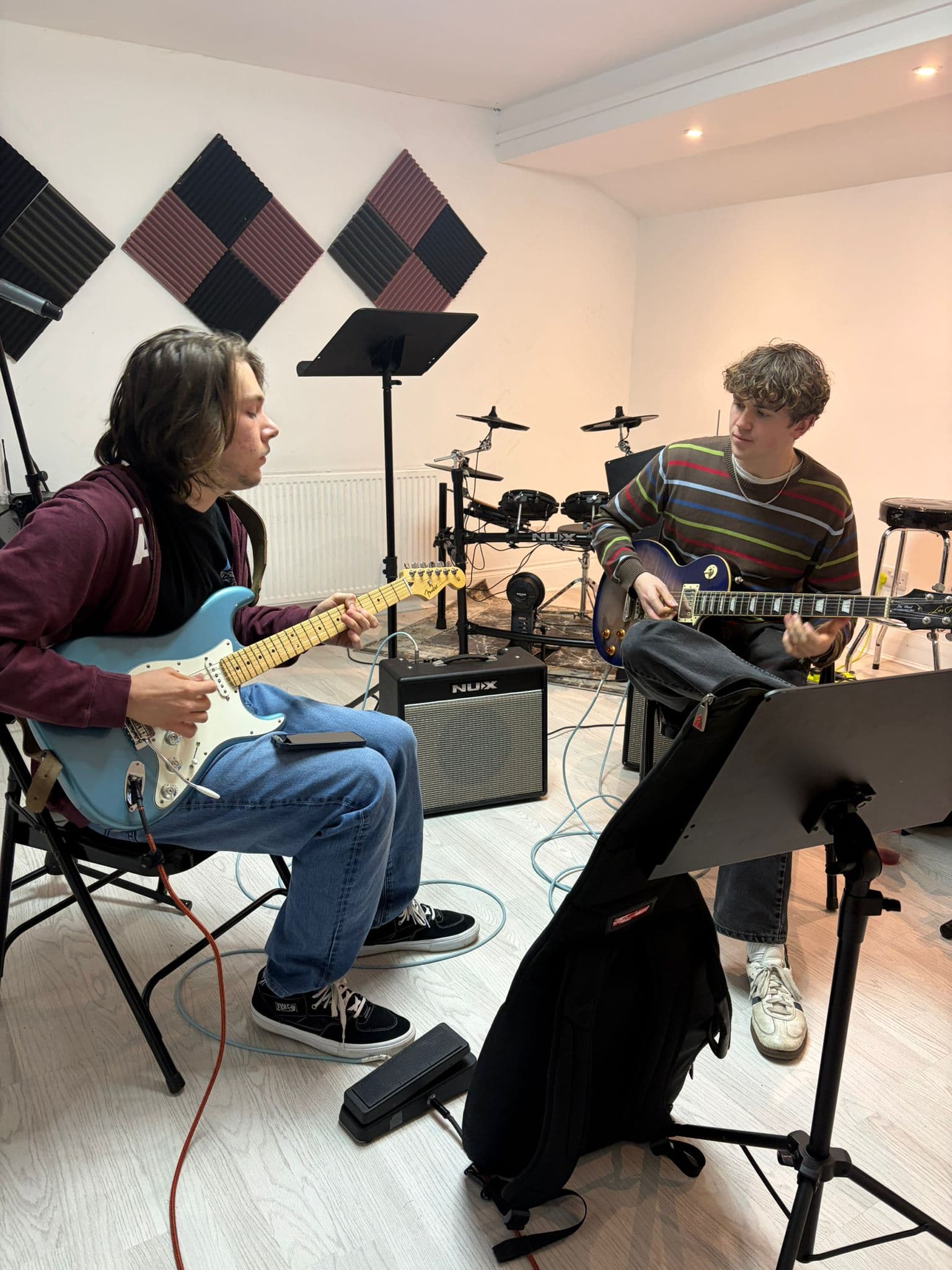 Two guitarists playing together in the rehearsal room