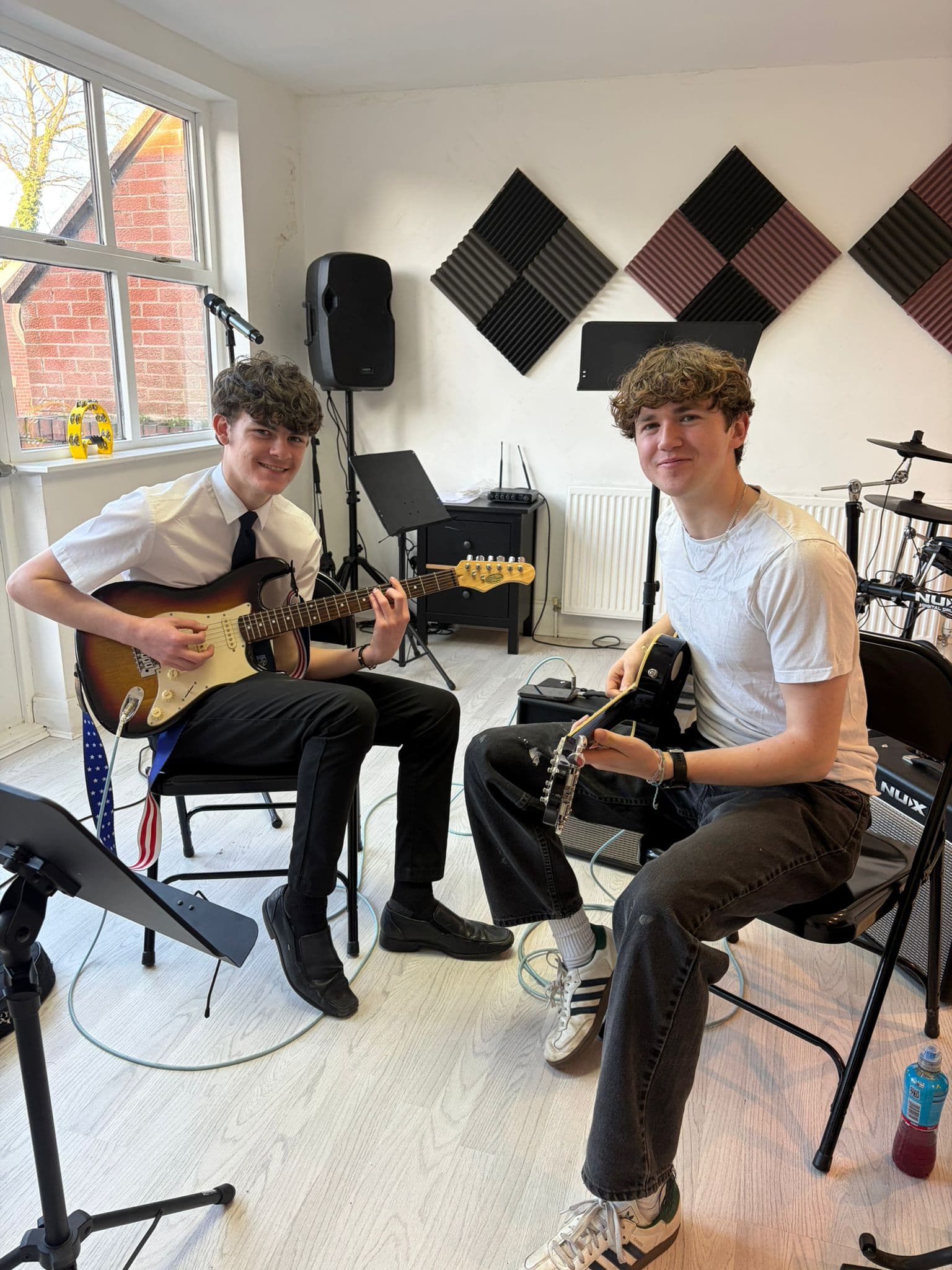 Two guitar students smiling during a rehearsal
